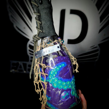 Hand holding ID fabrications OCtopus in a bottle with metal name tag