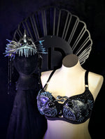 Black fish-themed bra on a mannequin with decorative headpiece against a dark background