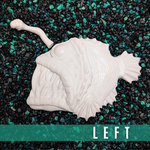 White fish-shaped object on a textured black and green surface with 'LEFT' text.