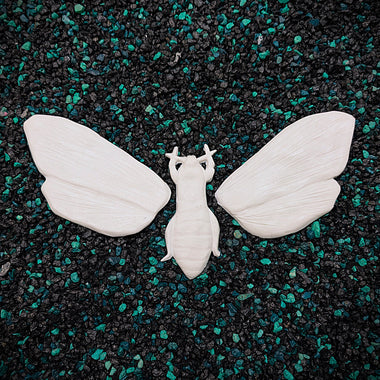 White moth figurine on a black and green speckled surface