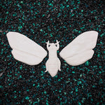 White moth figurine on a black and green speckled surface