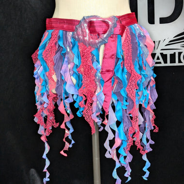 Colorful ruffled skirt on a mannequin against a black background with a logo.