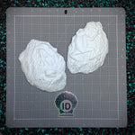 Two white textured objects on a gray cutting mat with a visible brand logo.