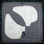 White silicone mold shaped like butterfly wings on a gray cutting mat with grid lines.