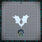 White bat-shaped object on a gray cutting mat with grid lines, featuring 'ID Fabrications' branding.