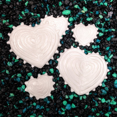 White heart-shaped cookies on a black and green sprinkled surface