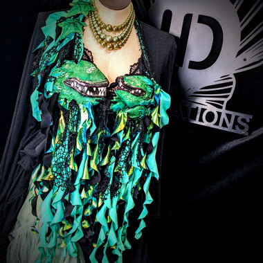 Mannequin wearing a green and black decorative garment with a brand logo in the background