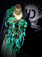 Mannequin wearing a green and black decorative garment with a brand logo in the background