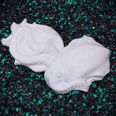 Two squid objects with tentacles on a dark surface with green specks