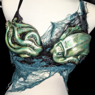 Mannequin wearing a bra with green alien-like squid designs on a black background