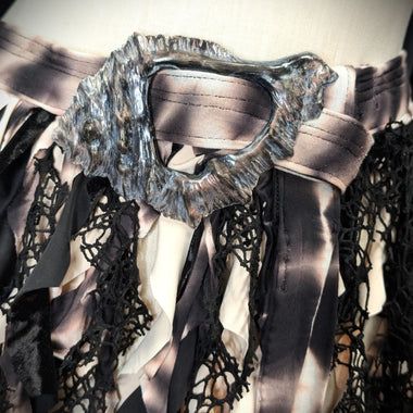 Close-up of a garment with intricate lace details and a metallic collar.