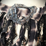 Close-up of a garment with intricate lace details and a metallic collar.