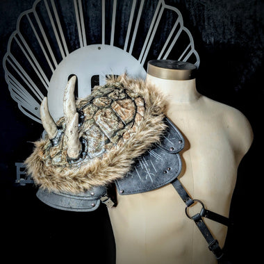 Decorative snapping turtle shell pauldron helmet with fur and leather details on a mannequin against a dark background