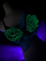 Green squid mermaid top glowing under a black light on a dark background