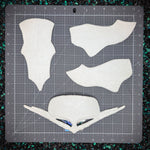 White plastic components on a gray cutting mat with measurements
