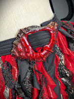 Close-up of a red and black costume with intricate details on a mannequin.