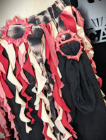 Colorful ruffled scarf on a hanger with decorative pink rings.