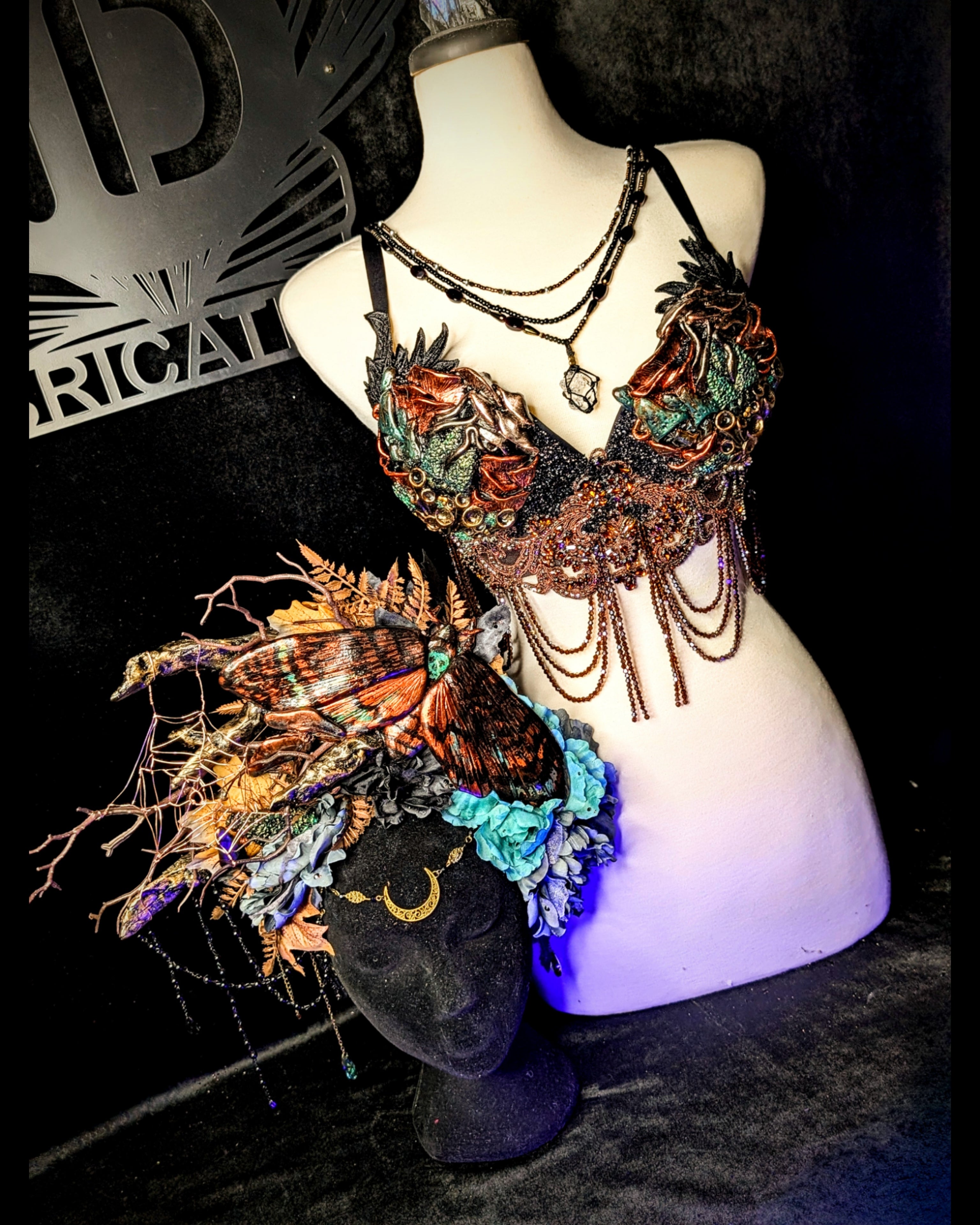 Decorative headpiece and bra on a mannequin against a dark background