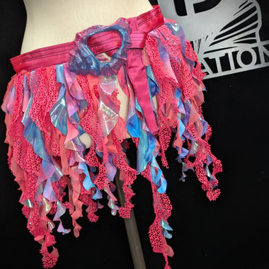 Mannequin wearing a colorful, ruffled pink and blue skirt with a black background.