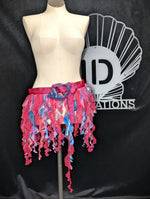 Colorful fringe skirt on a mannequin with a black background and logo.