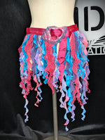 Colorful ruffled skirt on a mannequin against a black background with a logo.
