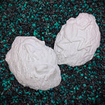 Two white ceramic mermaid figures on a black and green speckled surface