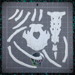 White resing seal skeleton parts on a gray cutting mat with grid lines.