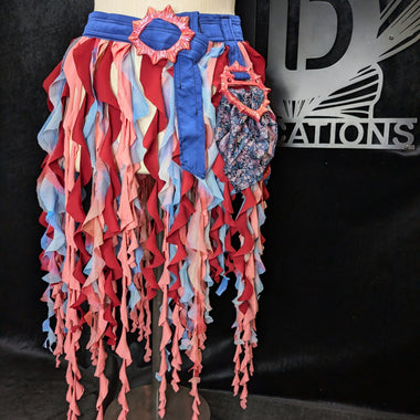 Colorful ruffled skirt on a mannequin against a black background with a logo.