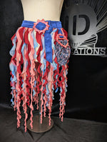 Colorful ruffled skirt on a mannequin against a black background with a logo.