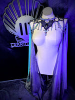 Mannequin wearing a decorative costume with a cape in front of a dark background with 'Fabric' branding.