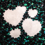 White heart-shaped cookies on a black and green sprinkled surface