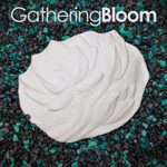 A white sculpted resin
plastic flower-shaped object with layered petals for DIY mermaid tops, placed on a bed of black and teal gravel. The text 'GatheringBloom' appears across the top.