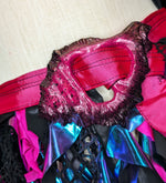 Close-up of a colorful pink and black conch shell buckle with pink and blue accents on a textured background